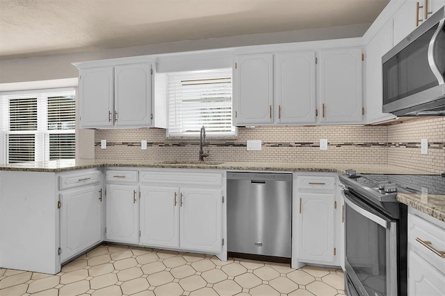 kitchen with stainless steel appliances, plenty of natural light, a sink, and light floors