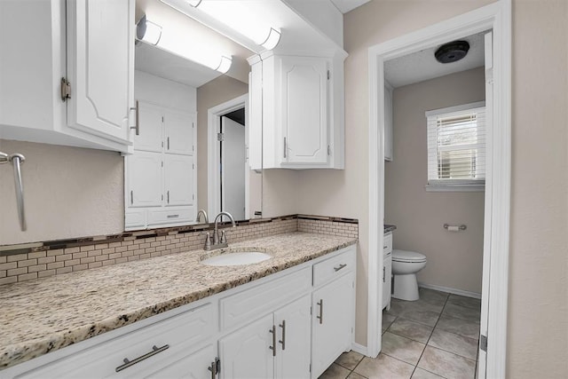bathroom with vanity, toilet, baseboards, tile patterned floors, and tasteful backsplash