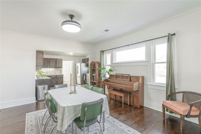 dining area with baseboards, ornamental molding, and dark wood finished floors