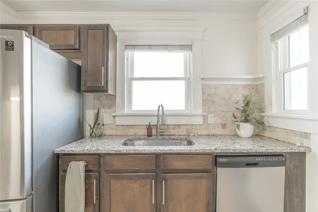 kitchen with a sink, appliances with stainless steel finishes, dark brown cabinetry, and a healthy amount of sunlight