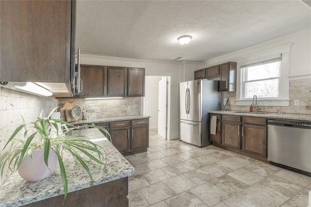 kitchen featuring a sink, light stone counters, decorative backsplash, and stainless steel appliances