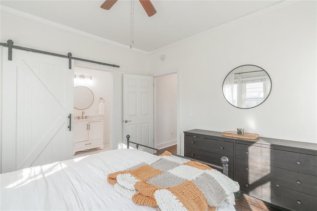 bedroom with ceiling fan, a sink, a barn door, and ornamental molding