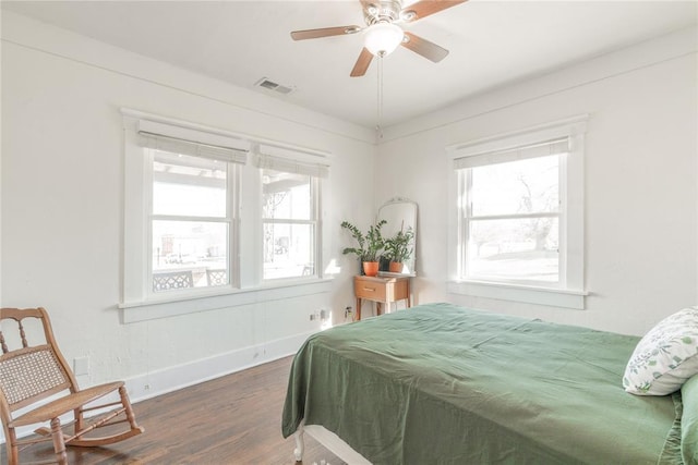 bedroom with baseboards, visible vents, multiple windows, and wood finished floors