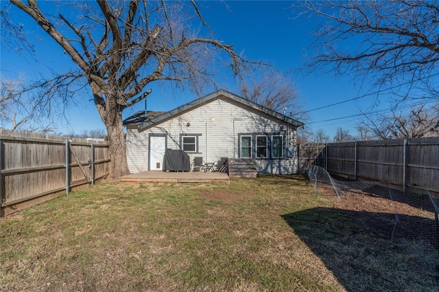 back of property featuring a fenced backyard, a yard, and a deck