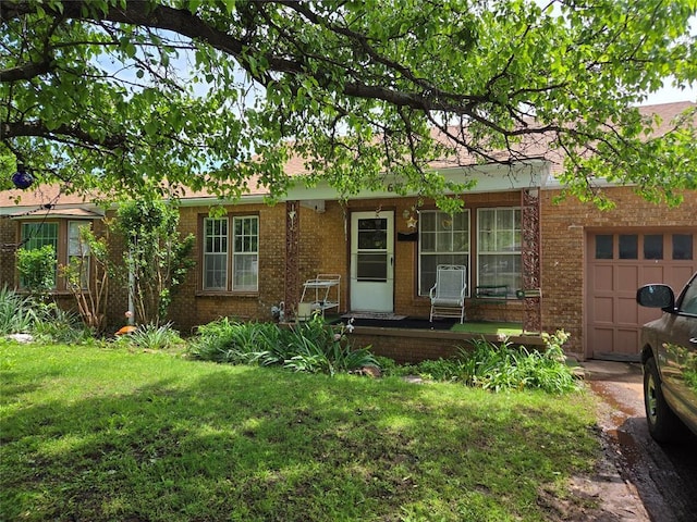 ranch-style house with covered porch, brick siding, a garage, and a front lawn