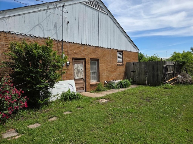 view of side of home featuring brick siding, fence, and a yard
