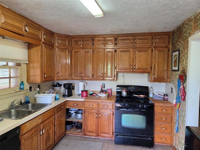 kitchen featuring a sink, brown cabinets, black appliances, and wallpapered walls