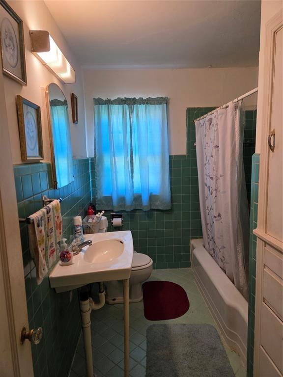full bath featuring toilet, tile patterned floors, a wainscoted wall, tile walls, and shower / tub combo