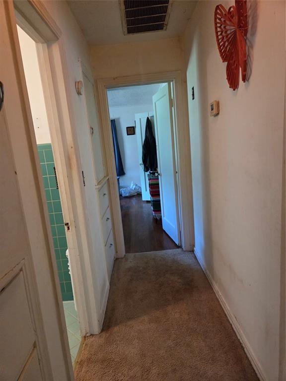 corridor featuring visible vents, carpet flooring, and baseboards