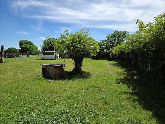 view of yard with fence, an outbuilding, and a storage unit