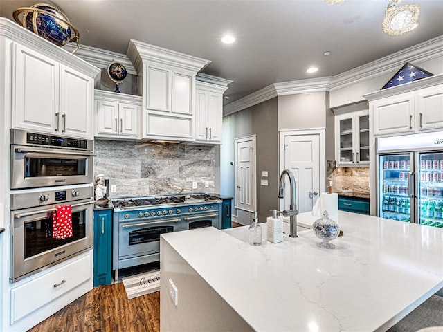 319 NE 1st St, Oklahoma City, OK 73104 - kitchen featuring white cabinets, high quality appliances, a large island with sink, backsplash, and ornamental molding