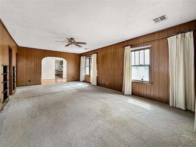 903 Sunset Dr, El Reno, OK 73036 - unfurnished living room with carpet flooring, arched walkways, a textured ceiling, a ceiling fan, and visible vents