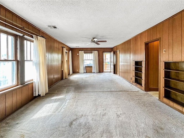903 Sunset Dr, El Reno, OK 73036 - unfurnished living room with visible vents, wood walls, carpet, and plenty of natural light