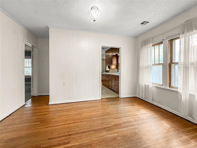 903 Sunset Dr, El Reno, OK 73036 - unfurnished room featuring a textured ceiling, light wood-style flooring, and a wealth of natural light