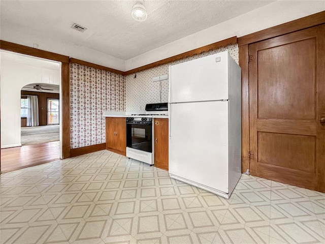 903 Sunset Dr, El Reno, OK 73036 - kitchen featuring visible vents, freestanding refrigerator, light countertops, brown cabinets, and range with gas cooktop