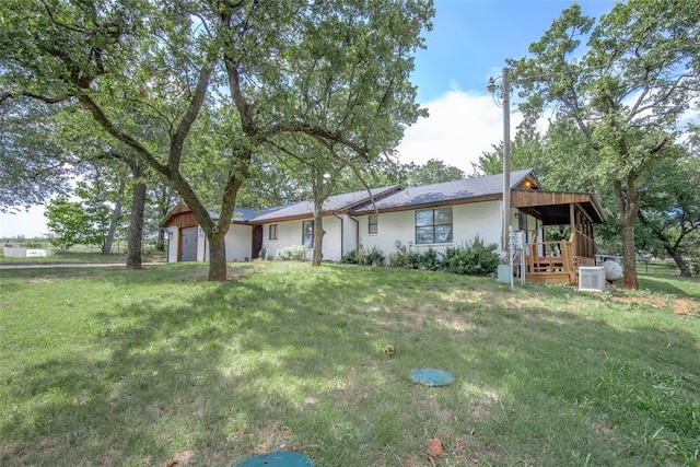 view of front facade with central AC unit, an attached garage, and a front lawn
