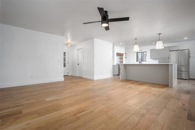 unfurnished living room with light wood-type flooring, a ceiling fan, baseboards, and recessed lighting
