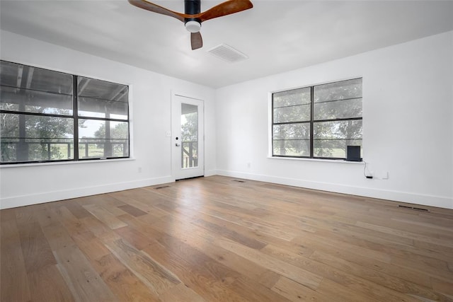 spare room featuring ceiling fan, visible vents, baseboards, and hardwood / wood-style floors