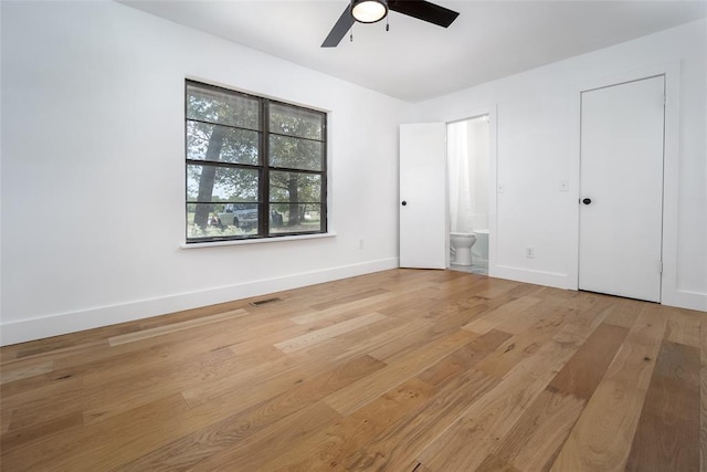 unfurnished bedroom featuring light wood finished floors, ensuite bath, a ceiling fan, baseboards, and visible vents