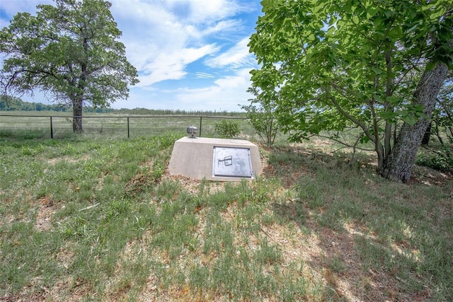 entry to storm shelter featuring fence and a rural view