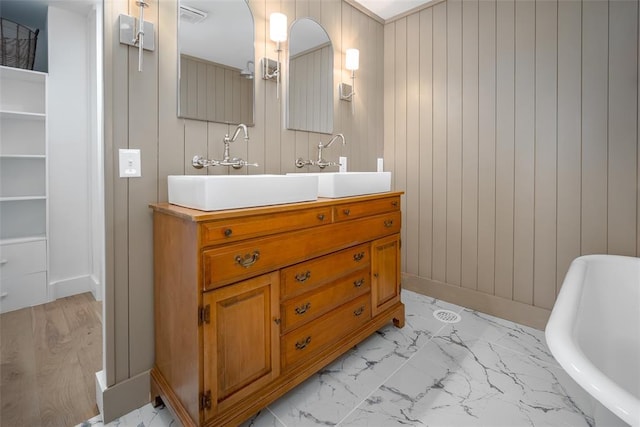 bathroom with a freestanding bath, vanity, marble finish floor, and visible vents