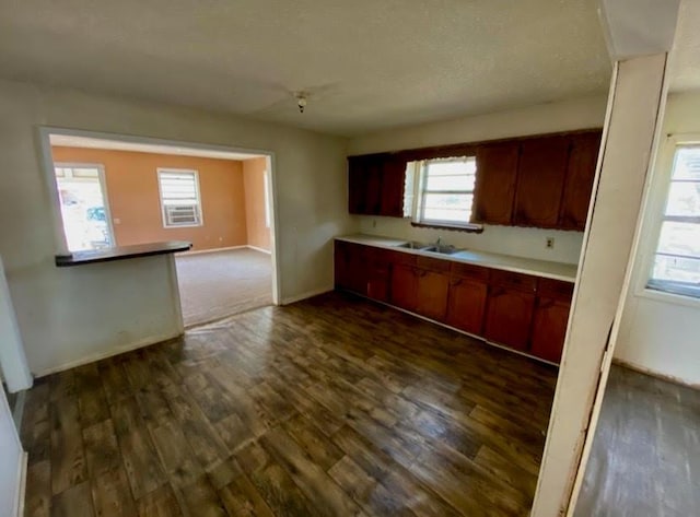 kitchen with light countertops, baseboards, a sink, and dark wood-type flooring