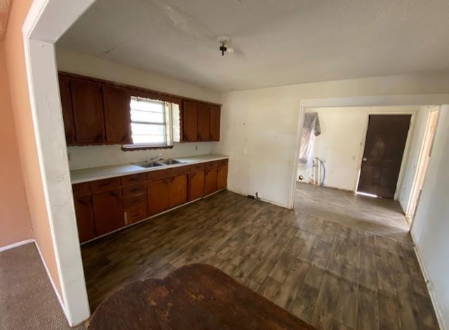 kitchen featuring a sink, light countertops, brown cabinetry, and dark wood finished floors