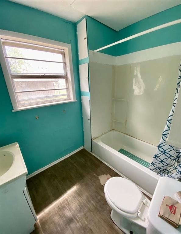 bathroom with shower / bath combo with shower curtain, wood finished floors, toilet, and vanity