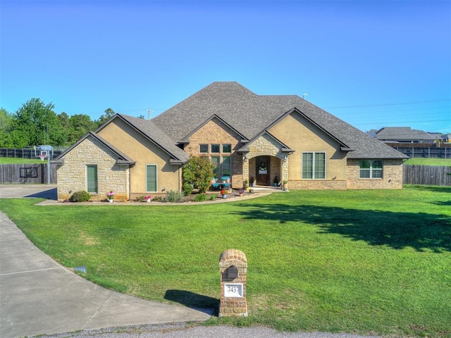 7437 SW 105th St, Oklahoma City, OK 73173 - view of front of home featuring fence, a front yard, roof with shingles, and stone siding