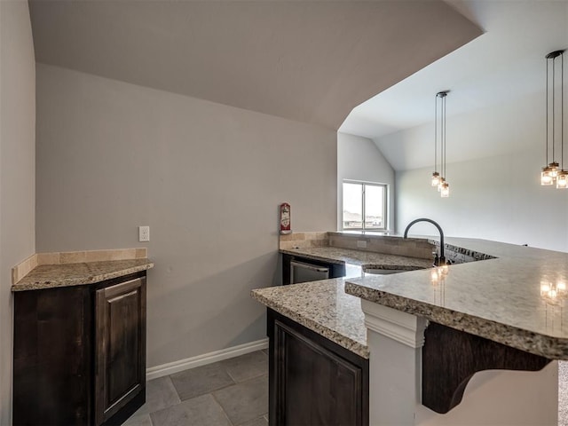 7437 SW 105th St, Oklahoma City, OK 73173 - kitchen featuring light stone countertops, dark brown cabinets, a sink, baseboards, and lofted ceiling