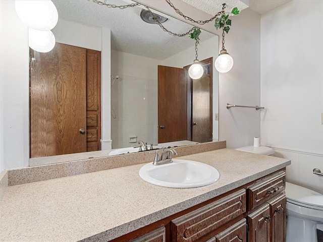 full bathroom featuring toilet, vanity, a textured ceiling, and a shower