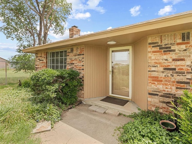 property entrance featuring a chimney and fence