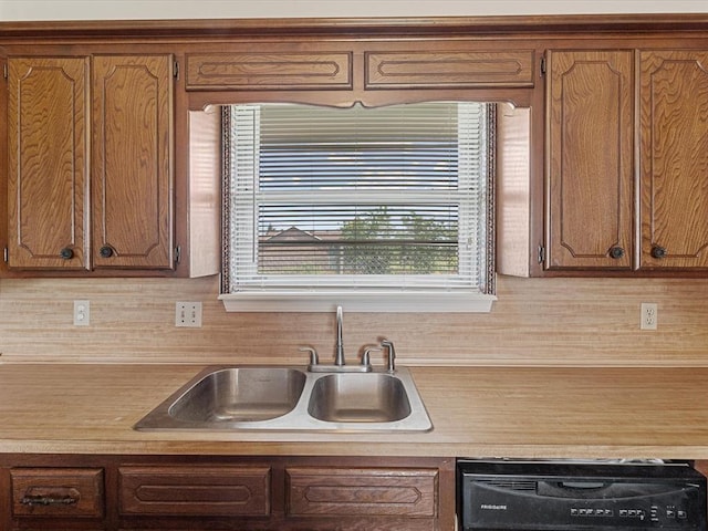 kitchen featuring dishwasher, a sink, brown cabinets, and light countertops