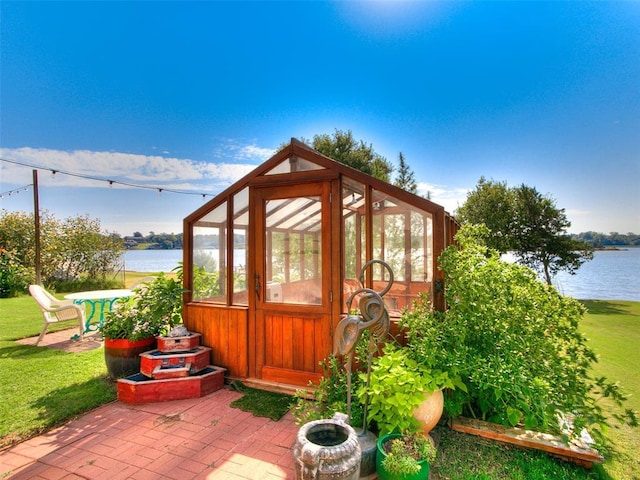 view of greenhouse with a lawn and a water view