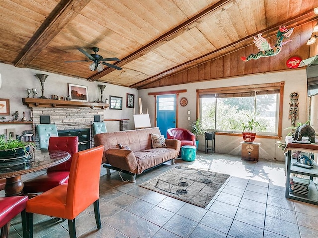 living area with wood ceiling, lofted ceiling with beams, a ceiling fan, and a stone fireplace