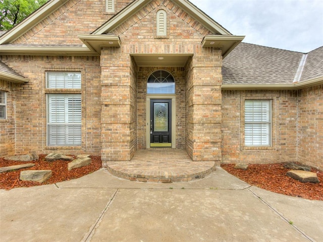 property entrance with roof with shingles and brick siding