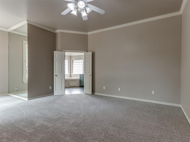 carpeted empty room with crown molding, baseboards, and a ceiling fan