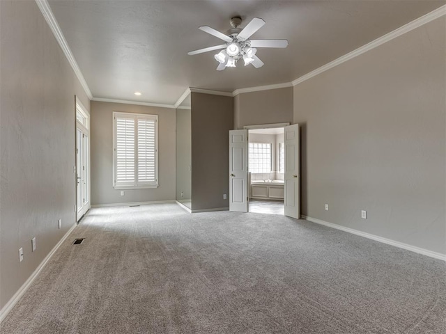 empty room with light colored carpet, ornamental molding, baseboards, and a ceiling fan