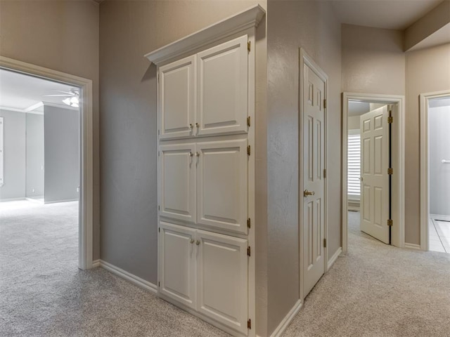corridor featuring baseboards and light colored carpet