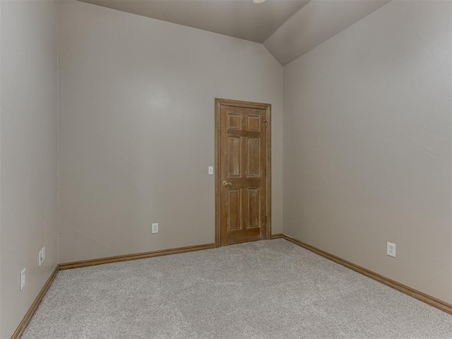 spare room featuring baseboards, carpet flooring, and lofted ceiling