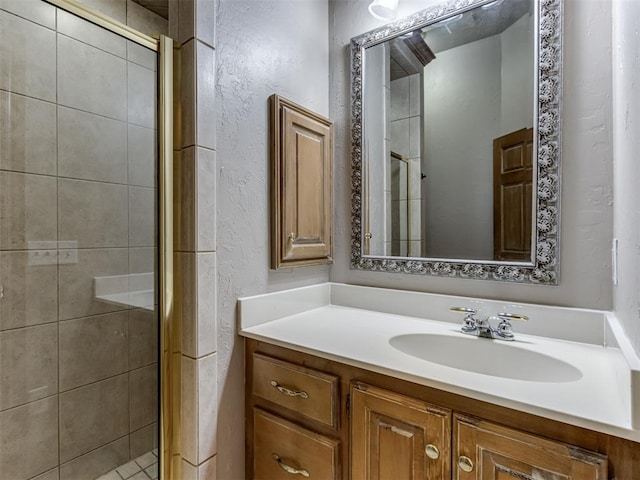 bathroom featuring a textured wall, a shower stall, and vanity