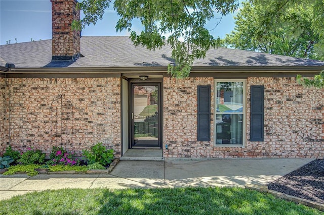 property entrance with roof with shingles and a chimney