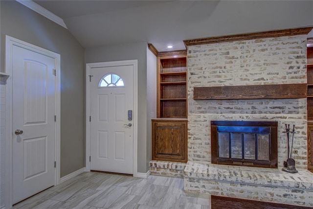 entrance foyer featuring vaulted ceiling, baseboards, and a brick fireplace