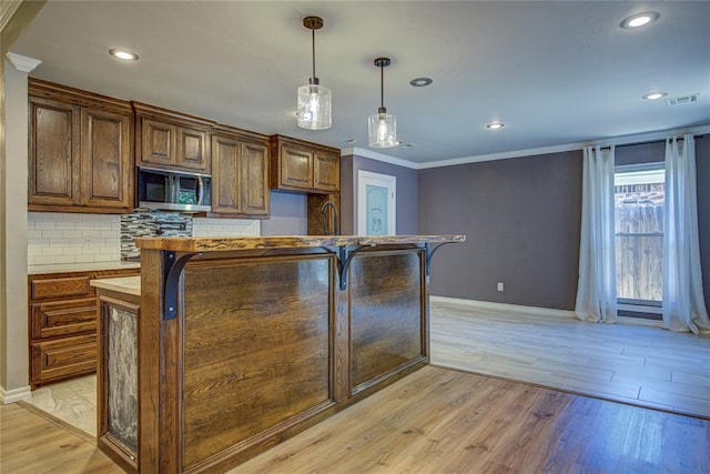 kitchen with recessed lighting, stainless steel microwave, decorative backsplash, and light wood finished floors
