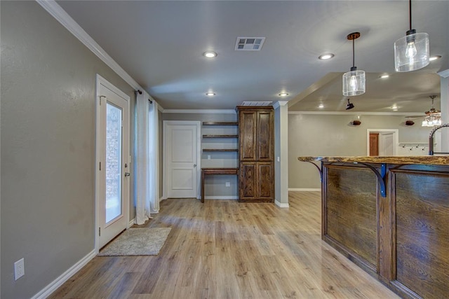 interior space with crown molding, baseboards, visible vents, and light wood-type flooring