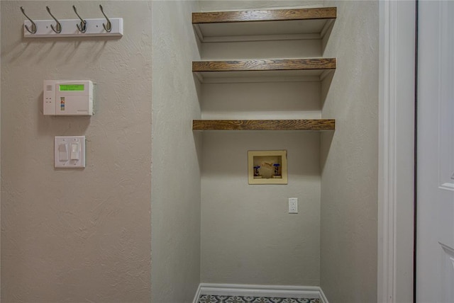laundry area with laundry area, a textured wall, baseboards, and hookup for a washing machine