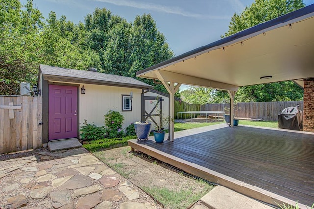 deck featuring a fenced backyard, an outbuilding, a trampoline, and a shed