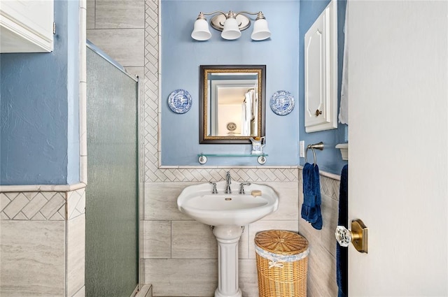 bathroom with tile walls, a wainscoted wall, and a shower stall