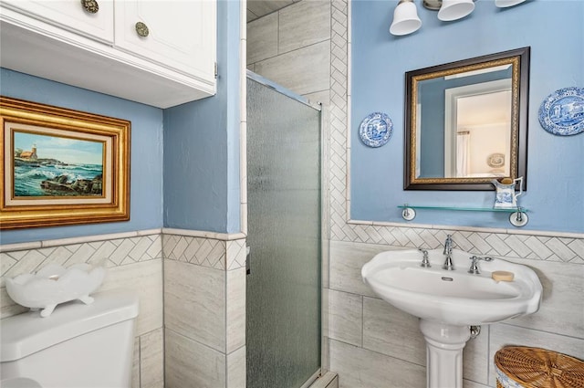 full bathroom featuring toilet, tile walls, a shower stall, and a wainscoted wall