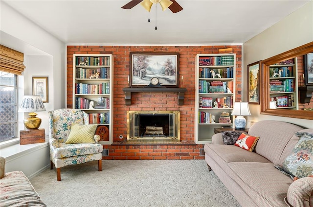 carpeted living area with a brick fireplace, ceiling fan, and built in features